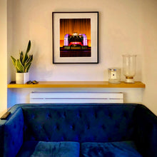 Load image into Gallery viewer, Framed Compton Organ The State artwork above a blue sofa with a plant and candle on a shelf.