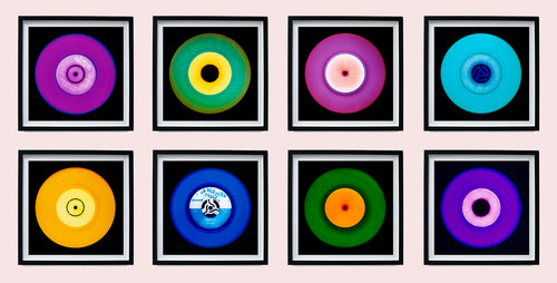 Photograph by Heidler and Heeps. Eight colourful vinyl records in black frames sit horizontally, 2 x 4.