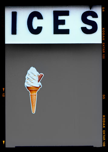 Photograph by Richard Heeps.  At the top black letters spell out ICES and below is depicted a 99 icecream cone sitting left of centre against a grey coloured background.  