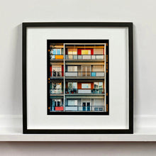 Load image into Gallery viewer, Black framed photograph by Richard Heeps. This is the balconies and balcony doors of 4 floors of flats located on the Rue Dezza. The colours of the walls alternate between red and grey but look different as the light catches them.