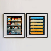 Load image into Gallery viewer, Two black framed photographs by Richard Heeps. The one on the left is the balconies and balcony doors of 4 floors of flats located on the Rue Dezza. The colours of the walls alternate between red and grey but look different as the light catches them. On the right hand side is 6 block coloured apartment balconies. Starting with light blue at the top, the next one yellow and then each in turn getting deeper in colour until there is an orange yellow on the bottom balcony.