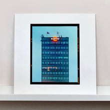 Load image into Gallery viewer, Mounted photograph by Richard Heeps. High rise offices in a blue light with Martini logo on the top facade.