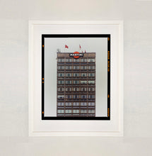 Load image into Gallery viewer, White framed photograph by Richard Heeps. High rise offices with Martini logo on the top facade.
