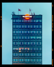 Load image into Gallery viewer, Photograph by Richard Heeps. High rise offices in a blue light with Martini logo on the top facade.