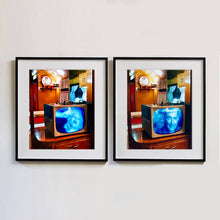 Load image into Gallery viewer, Two black framed photographs by Richard Heeps. Both photographs show a retro small brown television sitting on a wooden table displaying a black and white film, with the face of in turn Marilyn Monroe and Clark Gable, filling the screen, it shows as blue and white. In the background of the television is a warm wood-panelled light.