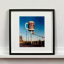 Load image into Gallery viewer, Black framed photograph by Richard Heeps. A giant model of a mug with Bob's Root Beer written on it sits on top of a giant pole. There is bunting hanging from the pole. It sits alongside a power line on a remote looking American country road.