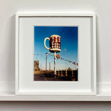 Load image into Gallery viewer, White framed photograph by Richard Heeps. A giant model of a mug with Bob's Root Beer written on it sits on top of a giant pole. There is bunting hanging from the pole. It sits alongside a power line on a remote looking American country road.