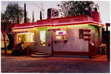 Load image into Gallery viewer, Photograph by Richard Heeps. This photograph depicts a one storey small building "Dot's Diner" brightly lit with a pink roof, with Hamburgers, Hot Dogs, Shakes, Fries written along the top width of the building.