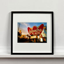 Load image into Gallery viewer, Black framed photograph by Richard Heeps. This photograph is of the outside of La Concha Motel. The gold flamboyant La Concha lettering is set on a big red background. Below the motel sign is NO VACANCY with just VACANCY lit in red, below this sits a sign for Budget rent a car. Other signs and palm trees are the background together with a blue sky.