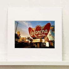 Load image into Gallery viewer, Mounted photograph by Richard Heeps. This photograph is of the outside of La Concha Motel. The gold flamboyant La Concha lettering is set on a big red background. Below the motel sign is NO VACANCY with just VACANCY lit in red, below this sits a sign for Budget rent a car. Other signs and palm trees are the background together with a blue sky.