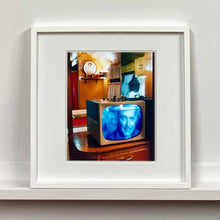 Load image into Gallery viewer, White framed photograph by Richard Heeps. A retro small brown television sits on a wooden table displaying a black and white film, with the face of Clark Gable filling the screen, it shows as blue and white. In the background of the television is a warm wood-panelled light.