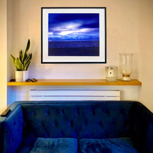 Load image into Gallery viewer, In situ photograph held by photographer Richard Heeps. A blue light hits vast land, mountains and a big sky.