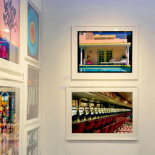 Load image into Gallery viewer, At the Art show - photographs by Richard Heeps. The top photograph shows Palm Springs Pool Side and showcases classic mid-century Palm Springs California architecture. Cool blue skies and pool with accents of pink and almost neon yellow. The bottom photograph features a row of slot machines and two rows of red chairs in front.