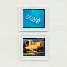 Load image into Gallery viewer, A pair of white framed photographs by Richard Heeps. The top photograph is of a transparent blue lilo sun bathing on a blue pool. The bottom photograph is a sand coloured building with a pool and sun loungers in front of it with a blue sky behind.