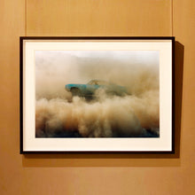 Load image into Gallery viewer, Black framed photograph by Richard Heeps. A side view of a light blue Buick car moving and slightly obscured by the dust clouds which it has created.