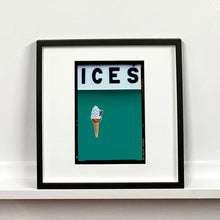 Load image into Gallery viewer, Black framed photograph by Richard Heeps.  At the top black letters spell out ICES and below is depicted a 99 icecream cone sitting left of centre against a deep green teal coloured background.