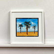 Load image into Gallery viewer, White framed photograph by Richard Heeps.  Three palm trees on the beach at Clacton-on-Sea with shadows cast by the early evening light.