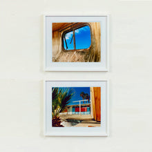 Load image into Gallery viewer, Two white framed photographs by Richard Heeps. The top photograph is of an interior of an eroded trailer, looking through the broken window to a deep blue sky. The bottom photograph is the outside of a brightly coloured motel, set against a blue sky. There is a palm tree at the side front of the scene.