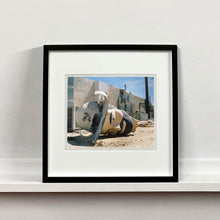 Load image into Gallery viewer, Black framed photograph by Richard Heeps. The broken off head of a giant fibreglass sculpture of a cowboy (a Muffler Man) lies on the ground.