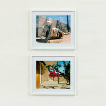 Load image into Gallery viewer, White framed photographs by Richard Heeps. At the top the photograph is of a broken off head of a giant fibreglass sculpture of a cowboy (a Muffler Man) lying on the ground. The photograph at the bottom in the front porch at a Motel with pink bougainvillea hanging in the middle of the photograph.