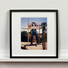 Load image into Gallery viewer, Black framed photograph by Richard Heeps. The headless torso of a giant fibreglass sculpture of a cowboy (a Muffler Man).