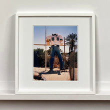 Load image into Gallery viewer, White framed photograph by Richard Heeps. The headless torso of a giant fibreglass sculpture of a cowboy (a Muffler Man).