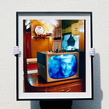 Load image into Gallery viewer, Black framed photograph by Richard Heeps. A retro small brown television sits on a wooden table displaying a black and white film, with the face of Clark Gable filling the screen, it shows as blue and white. In the background of the television is a warm wood-panelled light.
