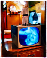 Load image into Gallery viewer, Photograph by Richard Heeps. A retro small brown television sits on a wooden table displaying a black and white film, with the face of Marilyn Monroe filling the screen, it shows as blue and white. In the background of the television is a warm wood-panelled light.