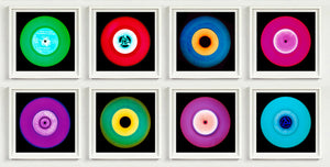 Photograph by Heidler and Heeps. Eight colourful vinyl records in white frames sit horizontally, 2 x 4.