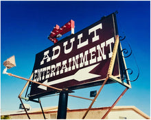 Load image into Gallery viewer, &#39;Adult Entertainment&#39; photographed in Beatty, Nevada, shows bold typography sitting prominently on an American road sign, against a background of bright blue sky. This fun and cheeky artwork was captured on a road trip through America and features in Richard Heeps&#39; sold out book &#39;Man&#39;s Ruin&#39;. An edition of this artwork recently sold at auction in The Auction Collective exhibition &#39;Hypercolor-Pop-Culture&#39;.