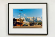 Load image into Gallery viewer, There is a cinematic style to this artwork, 'Lone Pine', taken in a former movie town in California where many Western films were made. Taken outside Richard's iconic interior photograph 'Bonanza Café', set in the Owens Valley against a mountainous  backdrop.