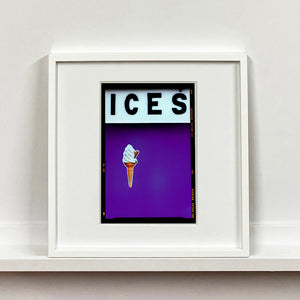 White framed photograph by Richard Heeps.  At the top black letters spell out ICES and below is depicted a 99 icecream cone sitting left of centre against a purple coloured background.  