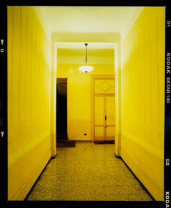 A yellow glow fills the corridor of an apartment foyer in Milan.