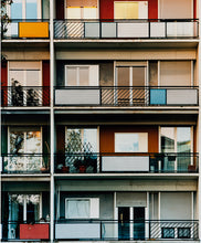 Load image into Gallery viewer, Photograph by Richard Heeps. This is the balconies and balcony doors of 4 floors of flats located on the Rue Dezza. The colours of the walls alternate between red and grey but look different as the light catches them.