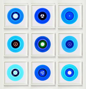 Photograph by Heidler and Heeps. A set of 9 different blue vinyls in white frames. They are displayed in a square 3 x 3 format.