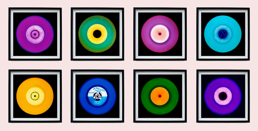 Photograph by Heidler and Heeps. Eight colourful vinyl records in black frames sit horizontally, 2 x 4.