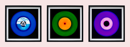 Photograph by Heidler and Heeps. 3 colourful vinyl records in a black frame sitting horizontally.