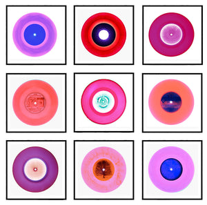 Photograph by Heidler and Heeps. A selection of 9 pink vinyl disks, set in white mounts, with black frames. Mounted in a 3x3 square.
