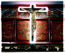 Load image into Gallery viewer, Photograph by Richard Heeps. A marble effect Jesus Christ statue hangs on a wooden cross which is surrounded with a white neon light. This sits against a wooden screen with gold carved patterns of flowers and butterlies.