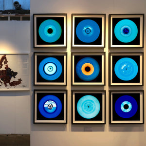 Photograph by Heidler and Heeps. A set of 9 different blue vinyls in a black frame in situ. They are displayed in a square 3 x 3 format.