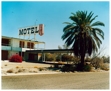 Load image into Gallery viewer, Photograph by Richard Heeps. A derelict motel office sits on a dusty American road. A large palm tree sits at the front of the office&#39;s walkway.