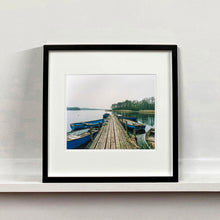 Load image into Gallery viewer, Ormesby Little Broad, a docking jetty with small boats stretches out to the Norfolk Broad photograph by Richard Heeps mounted square framed in black.