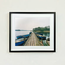 Load image into Gallery viewer, Ormesby Little Broad, a docking jetty with small boats stretches out to the Norfolk Broad photograph by Richard Heeps small framed in black.