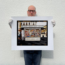 Load image into Gallery viewer, News Stand Milan, Italian street photography by Richard Heeps holding a medium print.