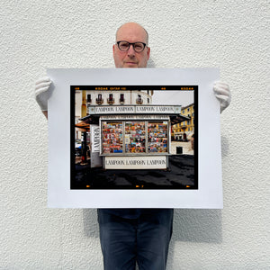 News Stand Milan, Italian street photography by Richard Heeps holding a medium print.