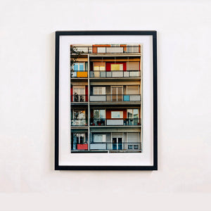 Black framed photograph by Richard Heeps. A colourful set of walls and balconies over five floors.
