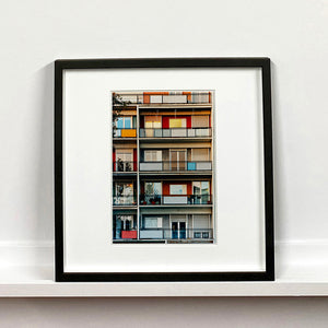 Black framed photograph by Richard Heeps. A colourful set of walls and balconies over five floors.