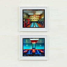 Load image into Gallery viewer, Two white framed photographs by Richard Heeps. The top one is of a laundrette with washing machines on each wall and a double sided seat in the middle. The bottom photograph is the inside of a restaurant with blue double sided seats, a blue wall and red tables.