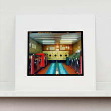 Load image into Gallery viewer, Mounted photograph by Richard Heeps. A laundrette with washing machines on each wall and a double sided seat in the middle.