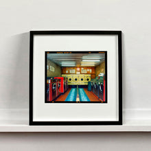 Load image into Gallery viewer, Black framed photograph by Richard Heeps. A laundrette with washing machines on each wall and a double sided seat in the middle.